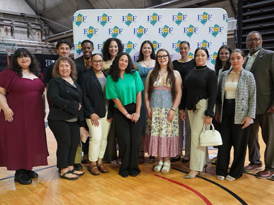 Group photo of students, faculty, and staff posing at an educational opportunity event in a gymnasium, standing in front of an EOF step-and-repeat banner.