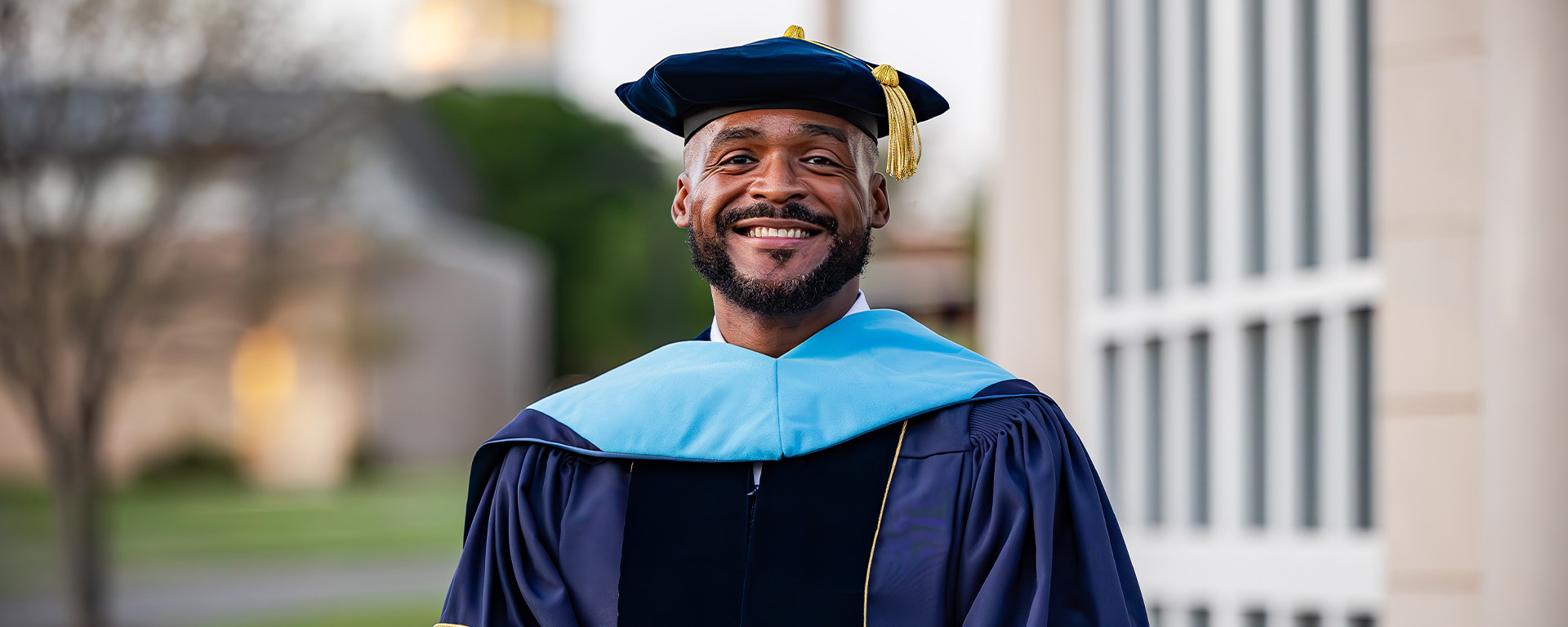 graduate man standing in front of building in regalia