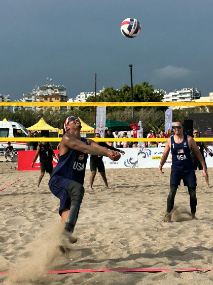 ranthony Two men play beach volleyball.